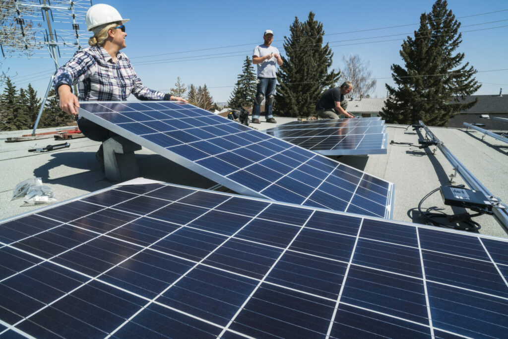 Workers installing solar panels on a residential homes roof.